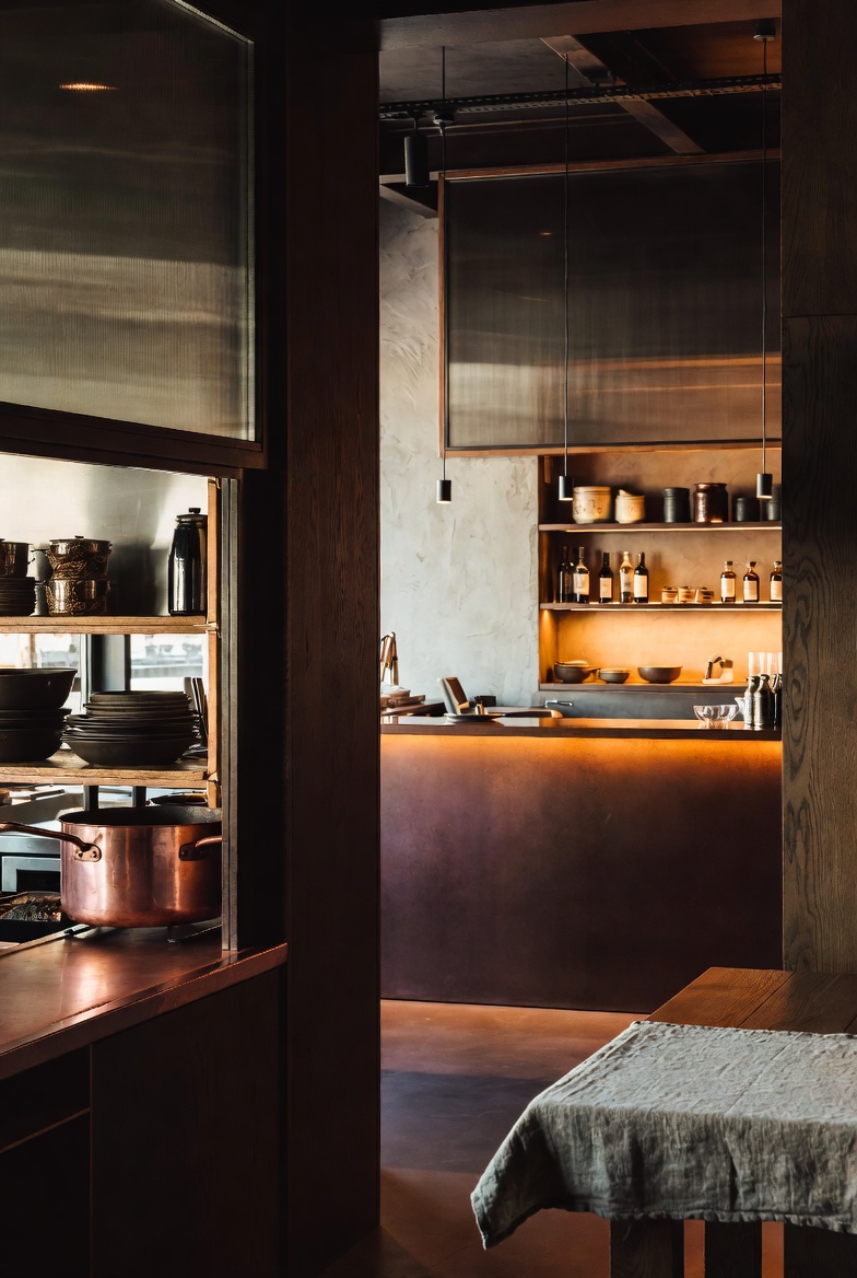 Warm port-side room portrait with dark wood, matte copper, and linen texture.
